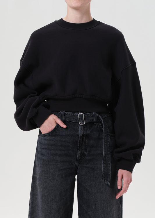 Person wearing a black oversized sweatshirt and black jeans on a white background
