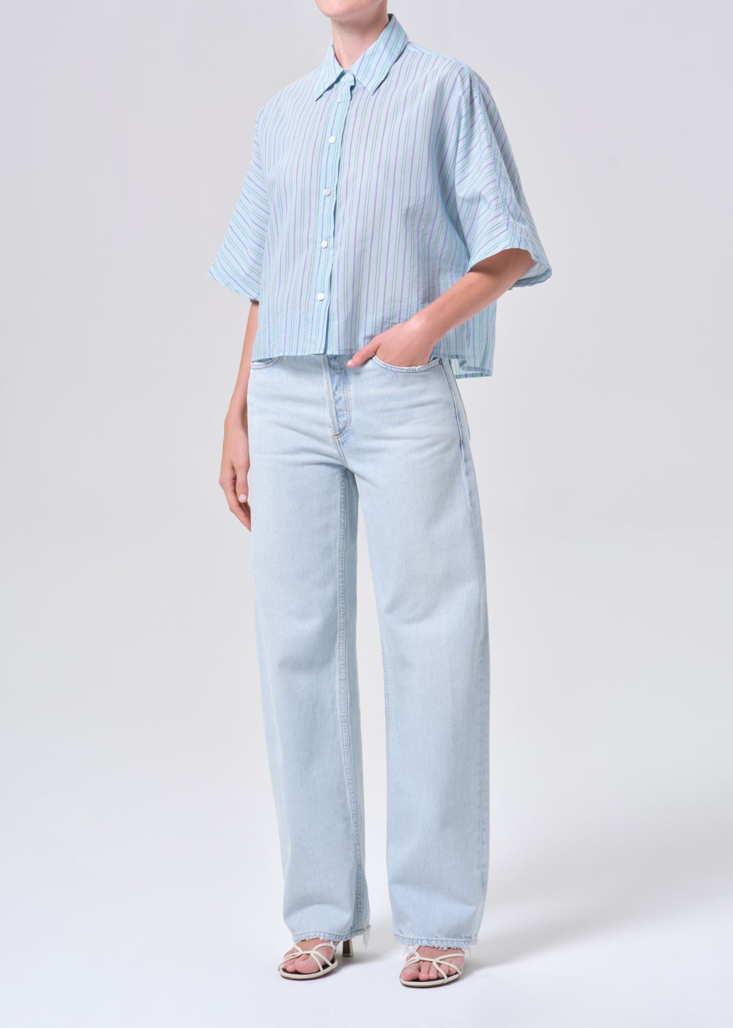 Person wearing a light blue striped shirt and pants on a white background