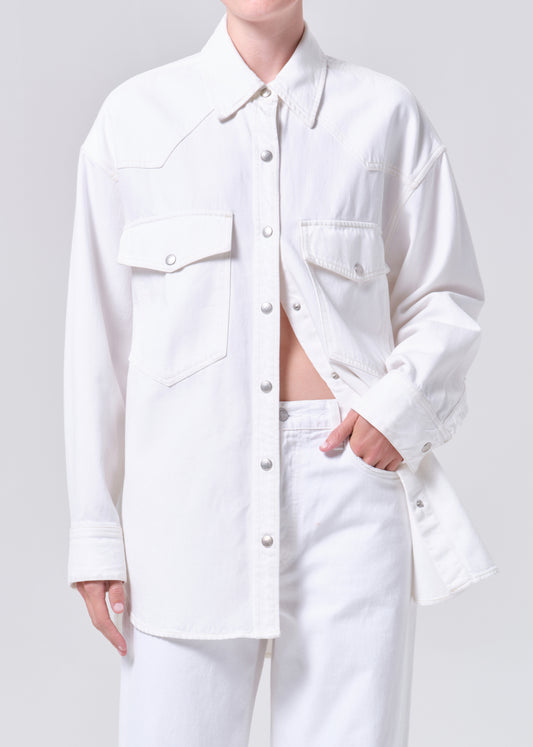 Person wearing a white denim jacket and pants on a plain background