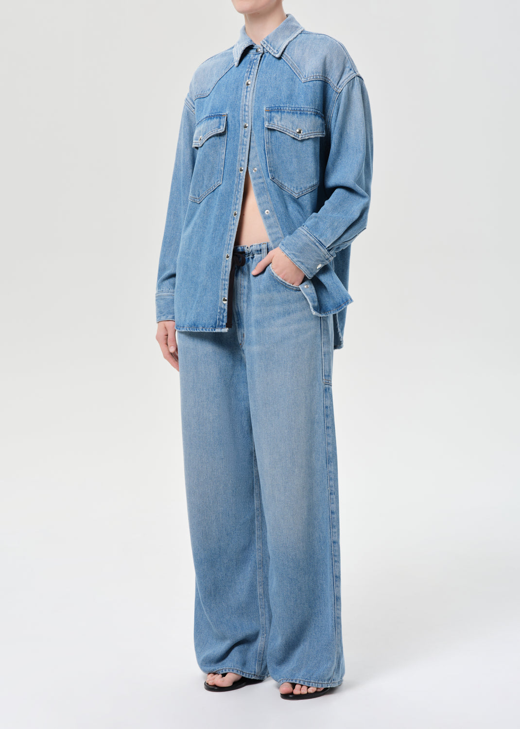 Person wearing a denim jacket and jeans on a white background