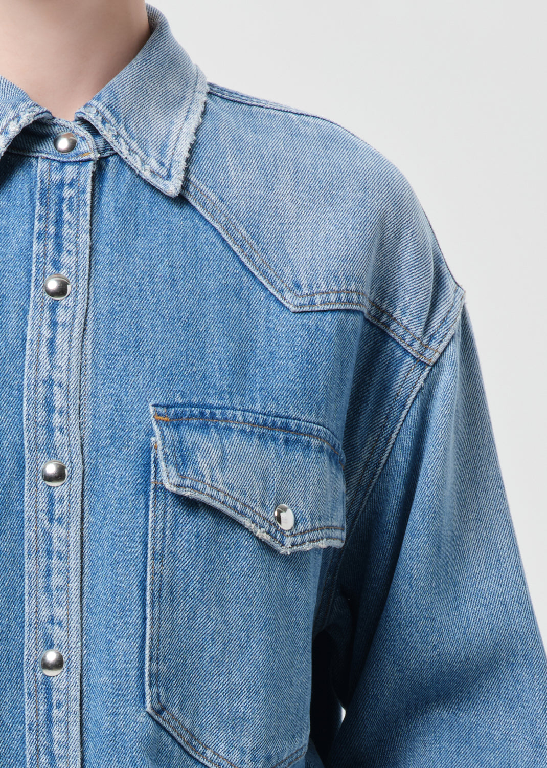 Close-up of a blue denim jacket on a mannequin with a plain background