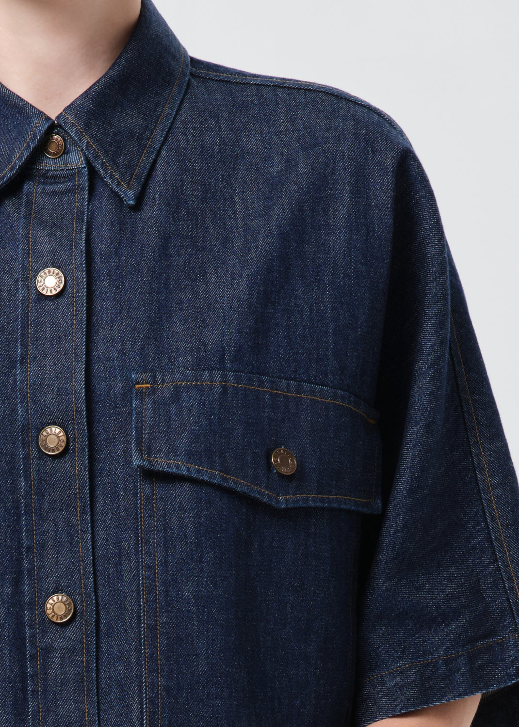 Close-up of a dark blue denim shirt with buttons on a plain background