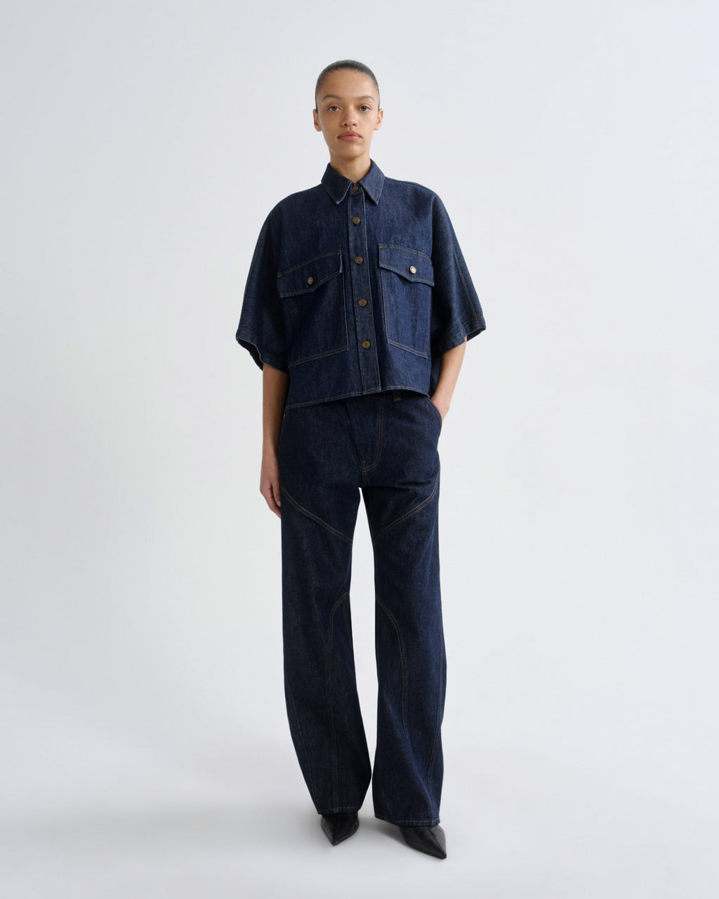 Person wearing a dark denim outfit on a white background
