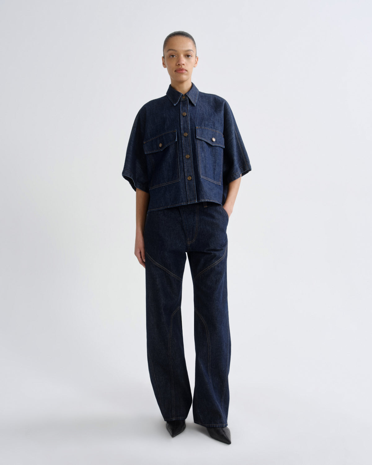 Person wearing a dark denim outfit on a white background