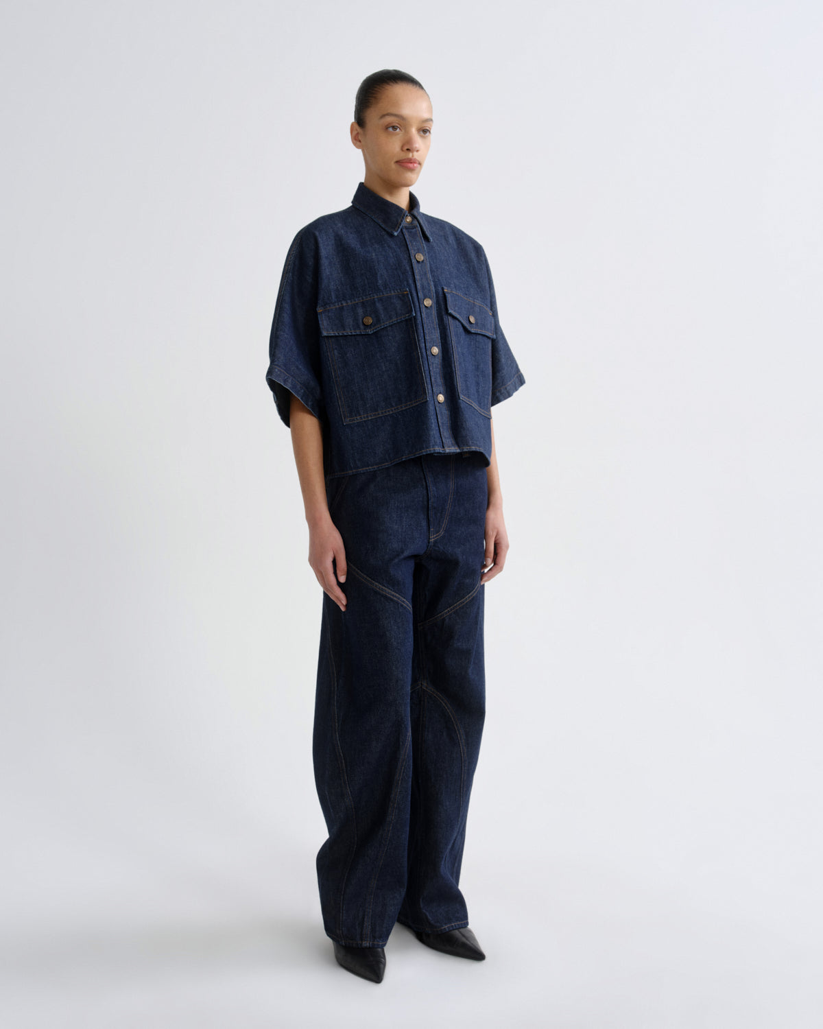 Person wearing a dark denim outfit on a white background