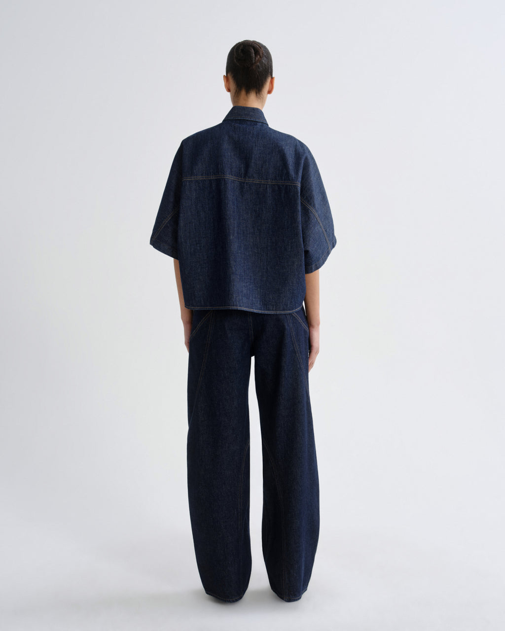 Person wearing a dark denim outfit on a white background