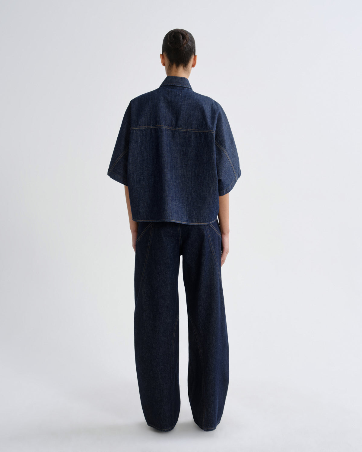 Person wearing a dark denim outfit on a white background