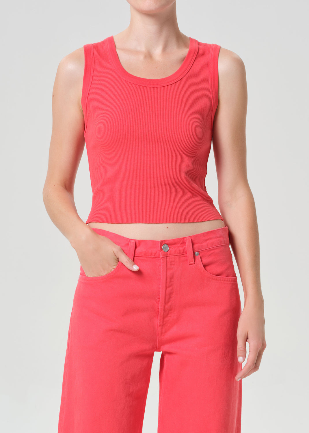 Person wearing a red sleeveless top and red pants on a gray background
