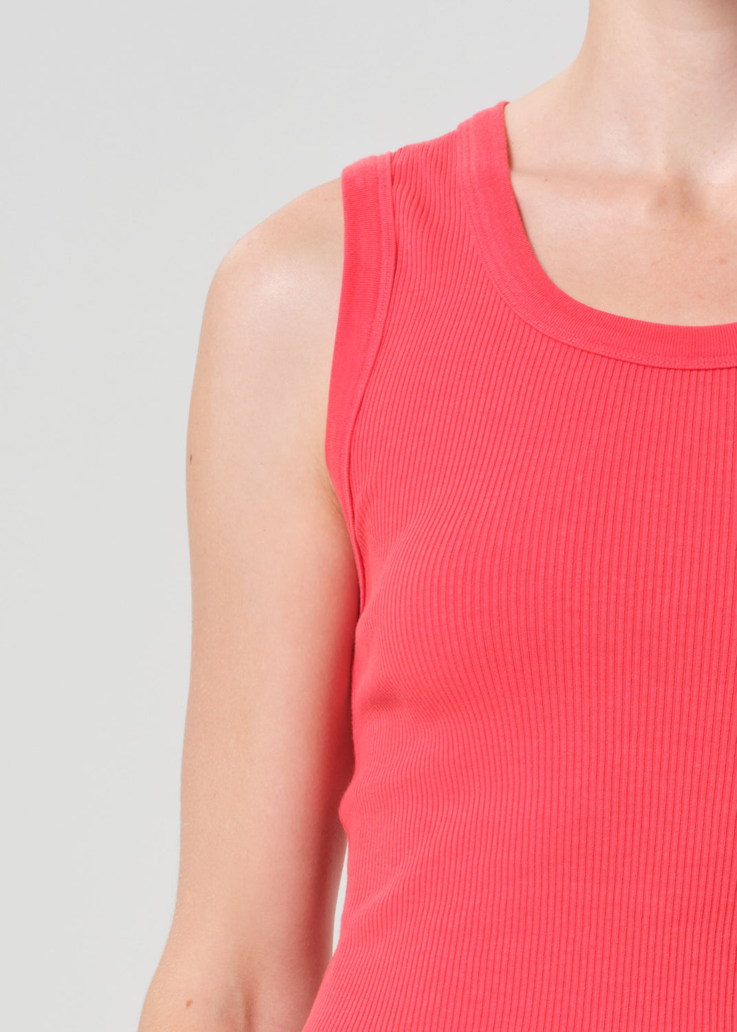 Close-up of a person wearing a red sleeveless top against a gray background