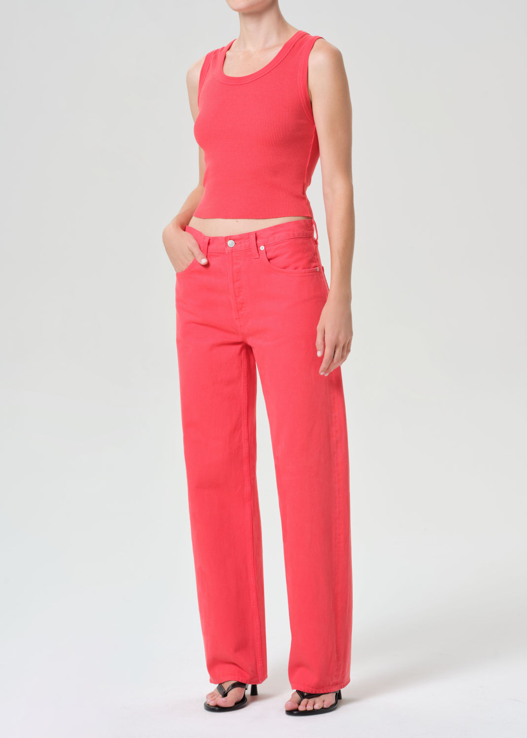 Person wearing a red sleeveless top and red pants on a white background