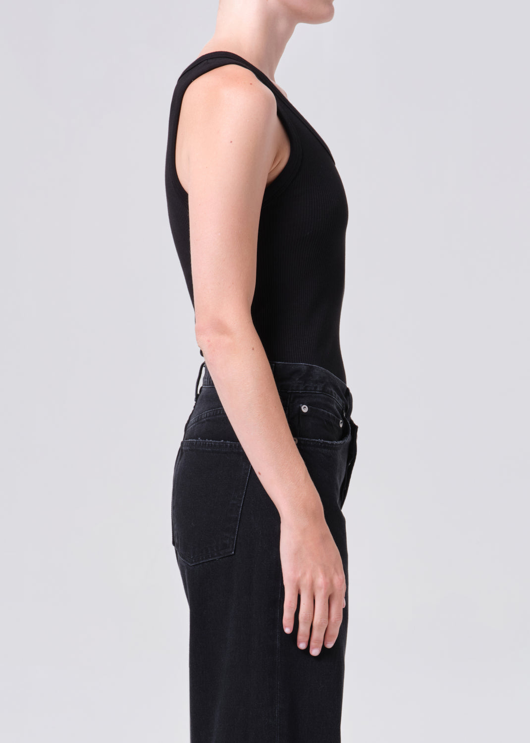 Person wearing a black sleeveless jumpsuit on a light gray background