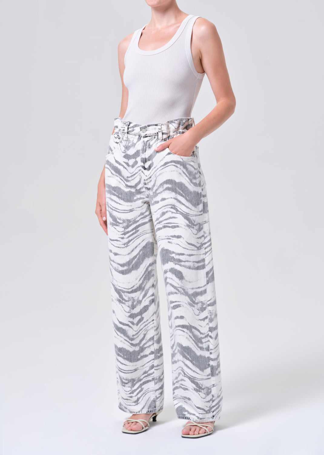 Person wearing white tank top and zebra print pants on a plain background