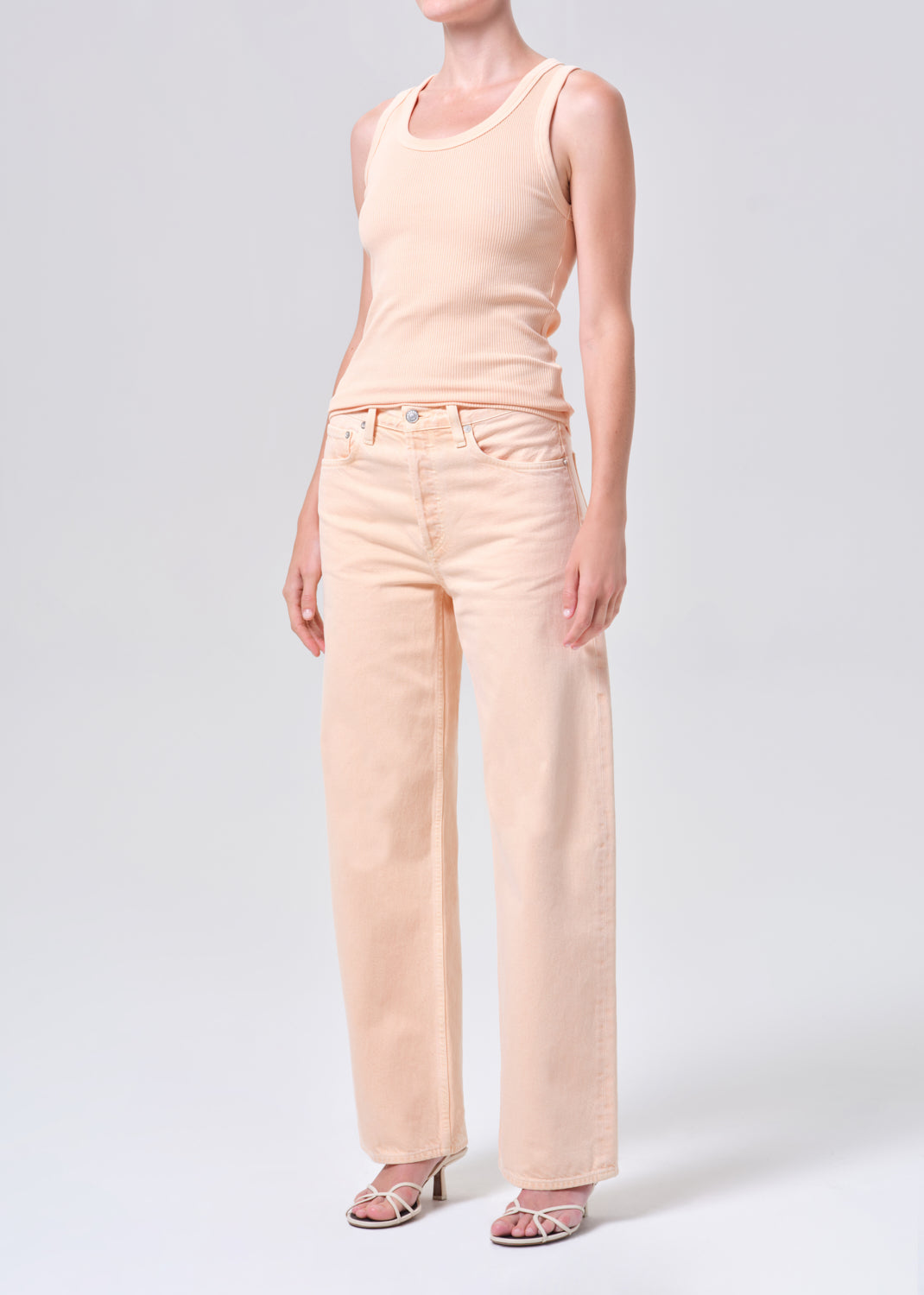 Person wearing a light pink tank top and pants on a white background