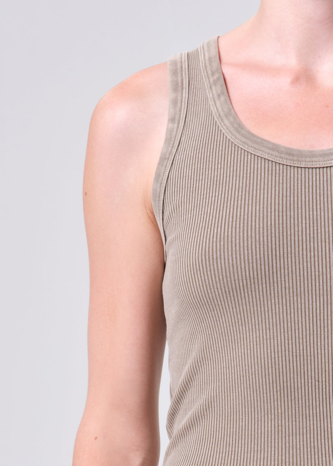 Person wearing a ribbed tank top against a plain background