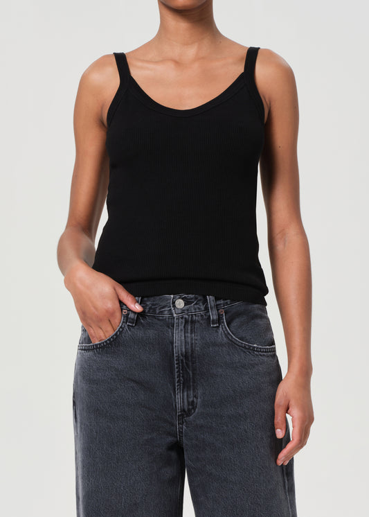 Person wearing a black tank top and dark jeans on a plain background