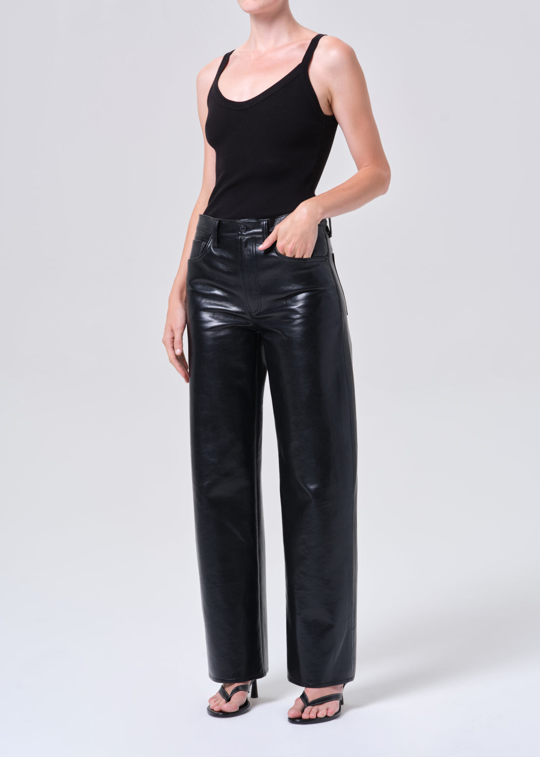 Person wearing black tank top and black leather pants on a white background