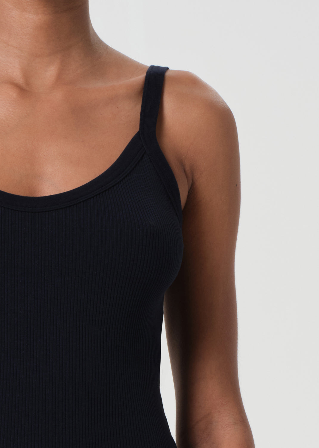 Black ribbed tank top worn by a person on a white background
