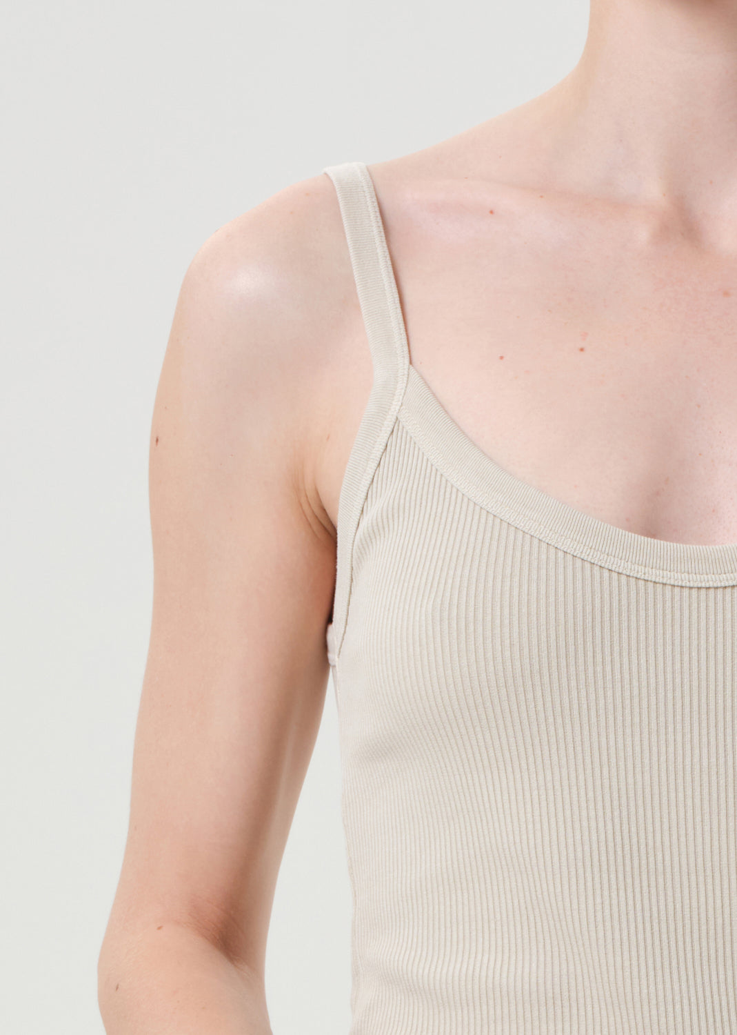 Beige ribbed tank top worn by a person on a light gray background