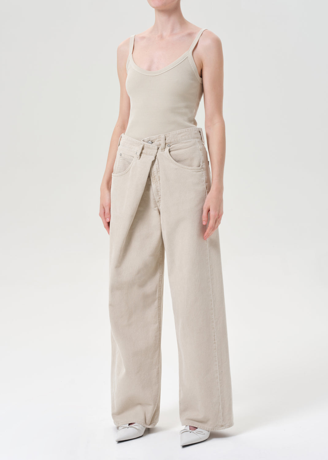 Person wearing a beige jumpsuit on a white background