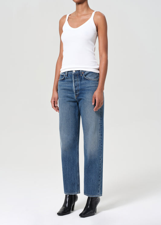 Person wearing a white tank top and blue jeans on a white background