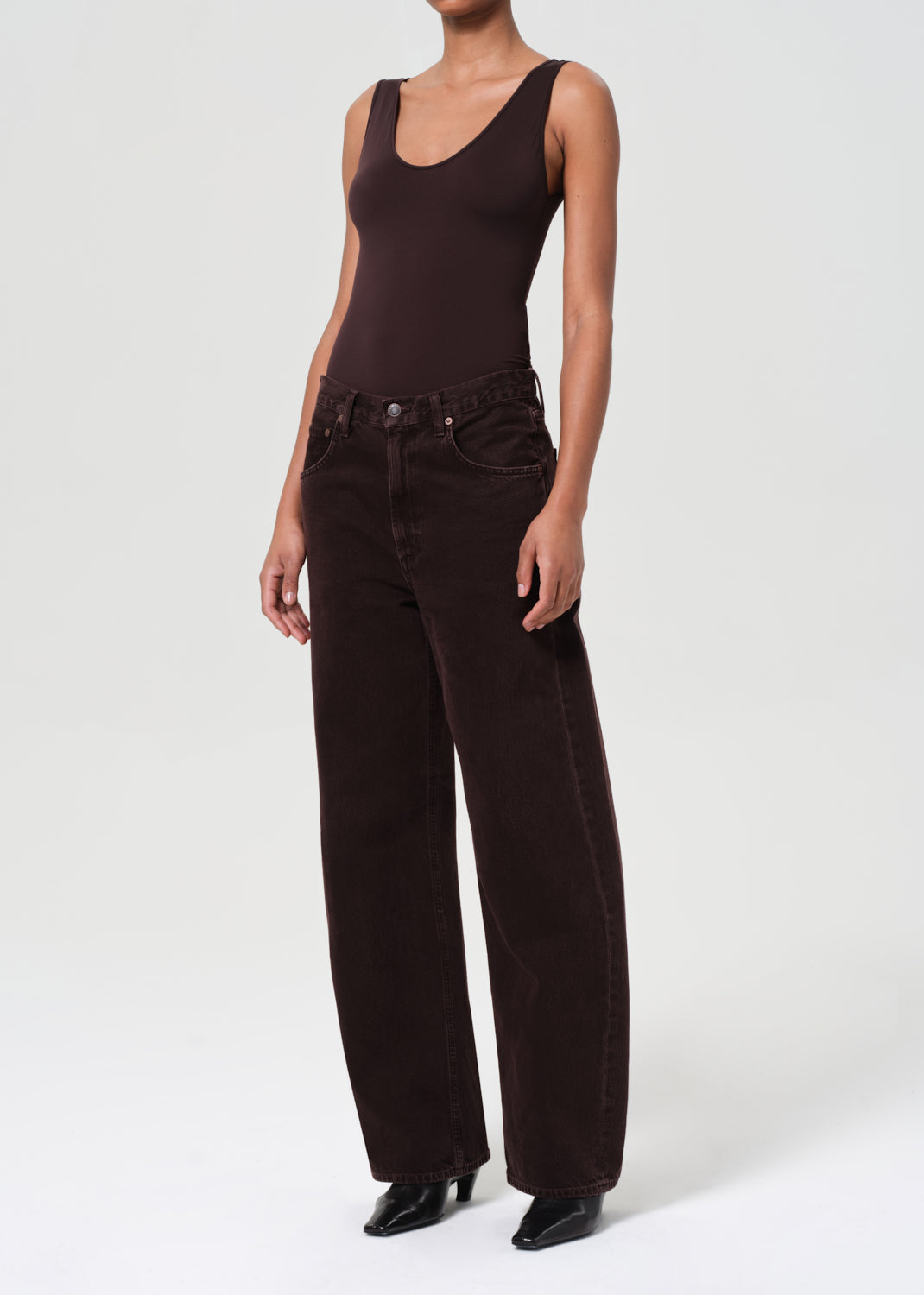 Person wearing a brown tank top and wide-leg pants on a white background