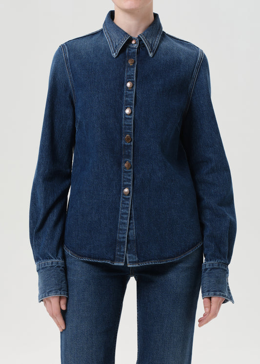 Blue denim shirt with button details on a plain background