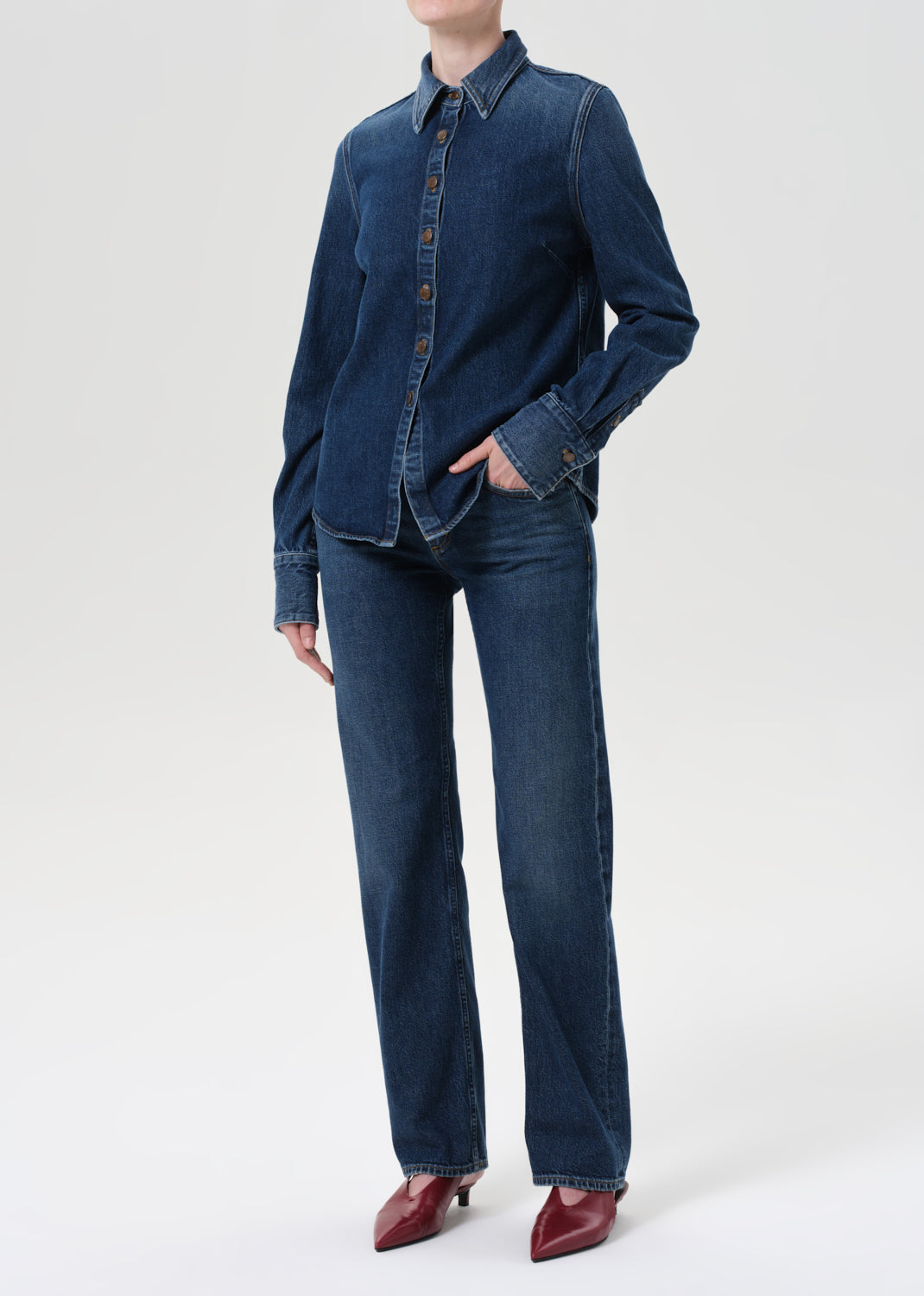 Person wearing a blue denim shirt and jeans on a white background