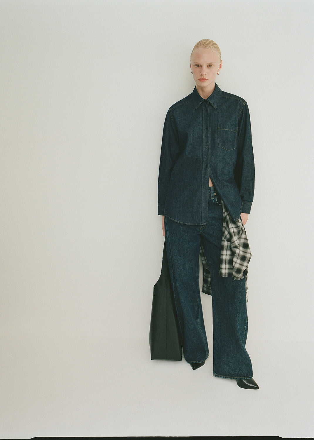 Person wearing a dark green outfit with plaid shirt on a white background