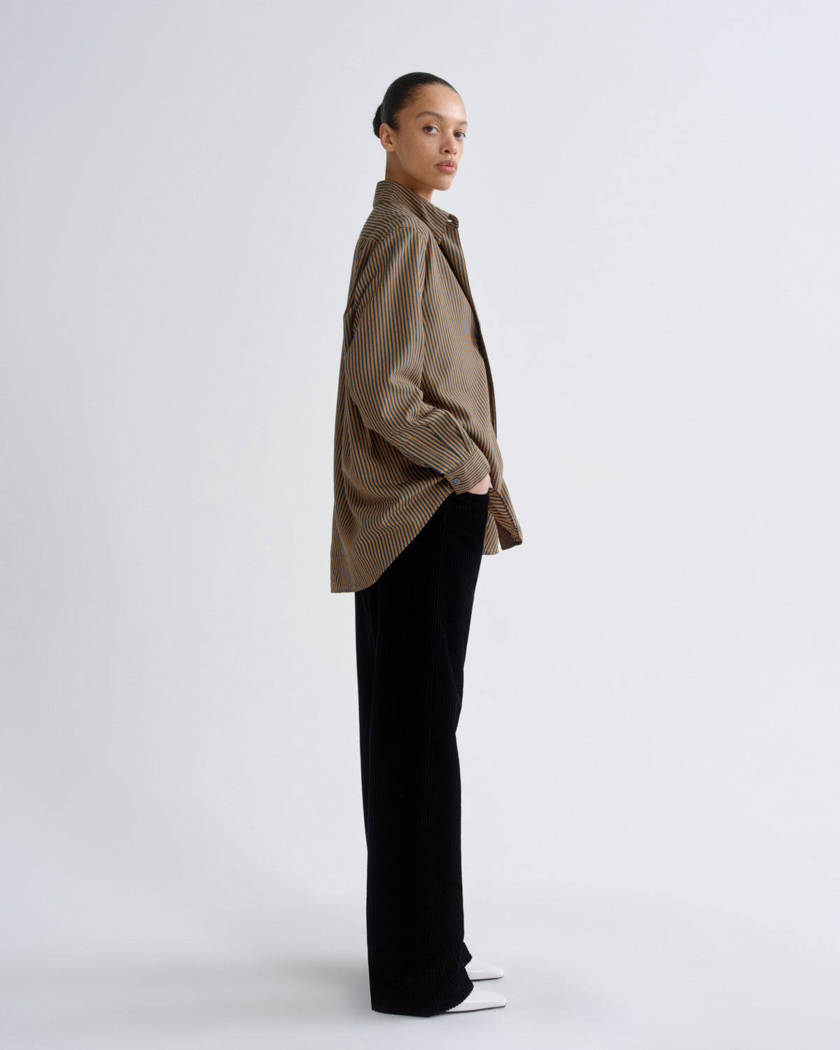 Person wearing a beige shirt and black pants on a white background