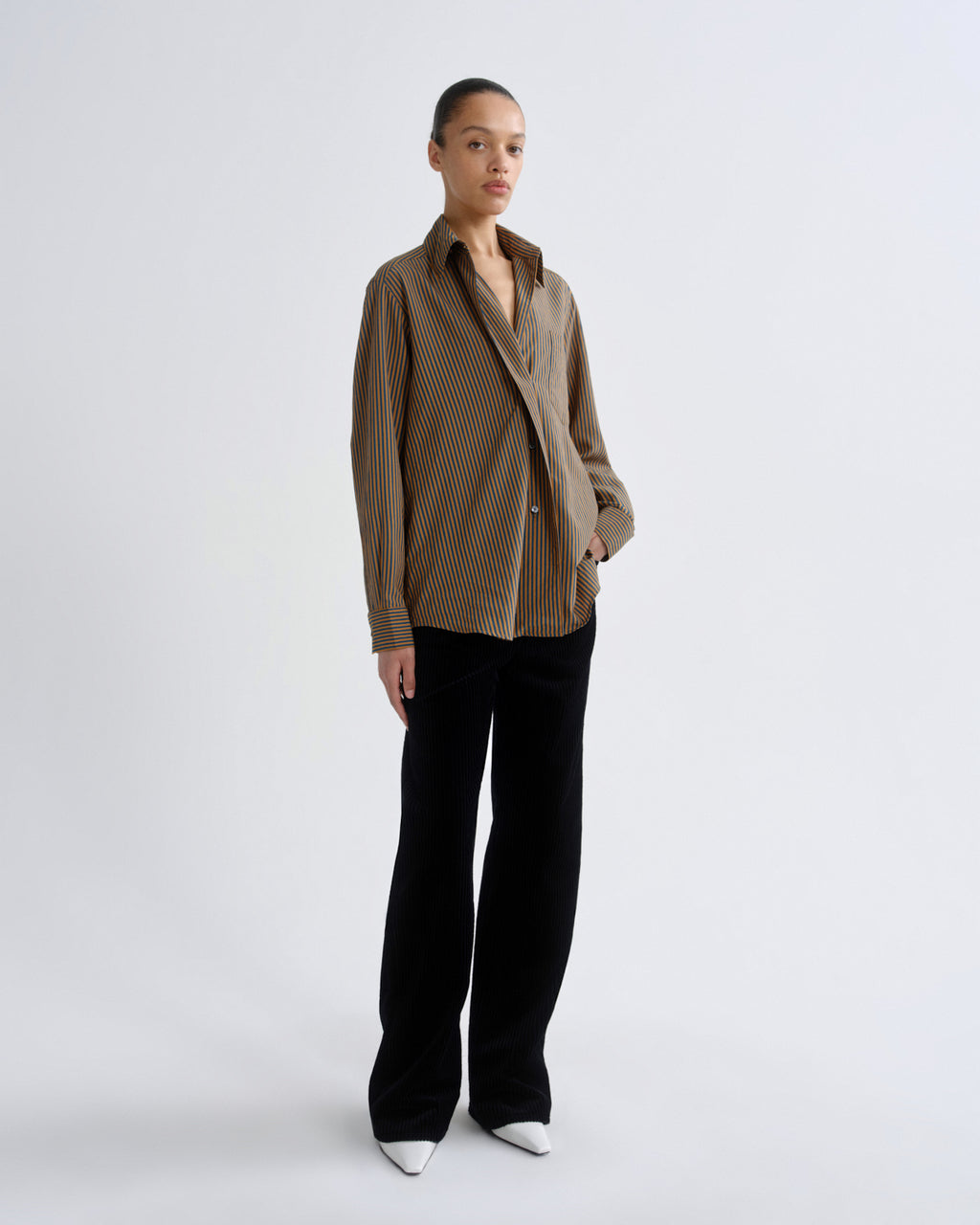 Woman wearing a brown checkered shirt and black pants on a white background