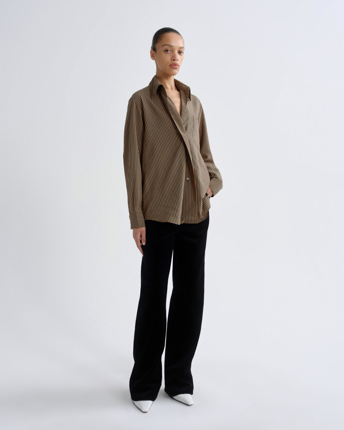 Woman wearing a brown checkered shirt and black pants on a white background