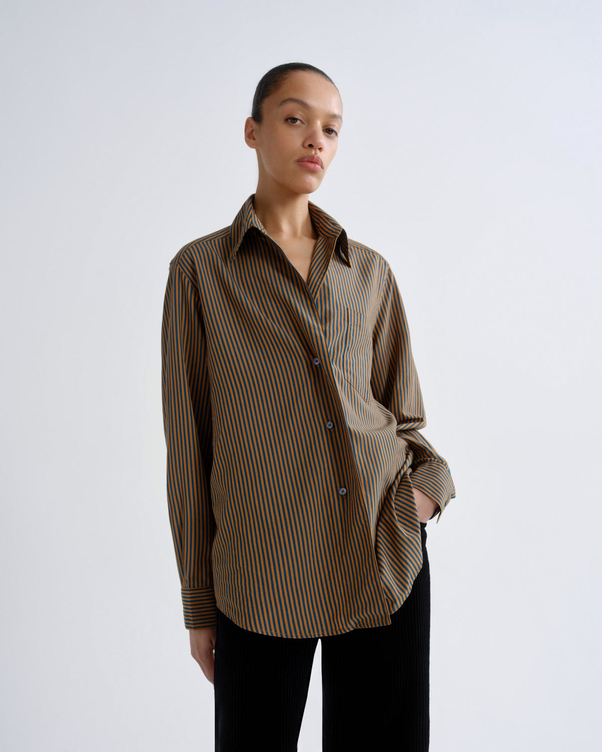 Woman wearing a brown and yellow striped shirt on a white background
