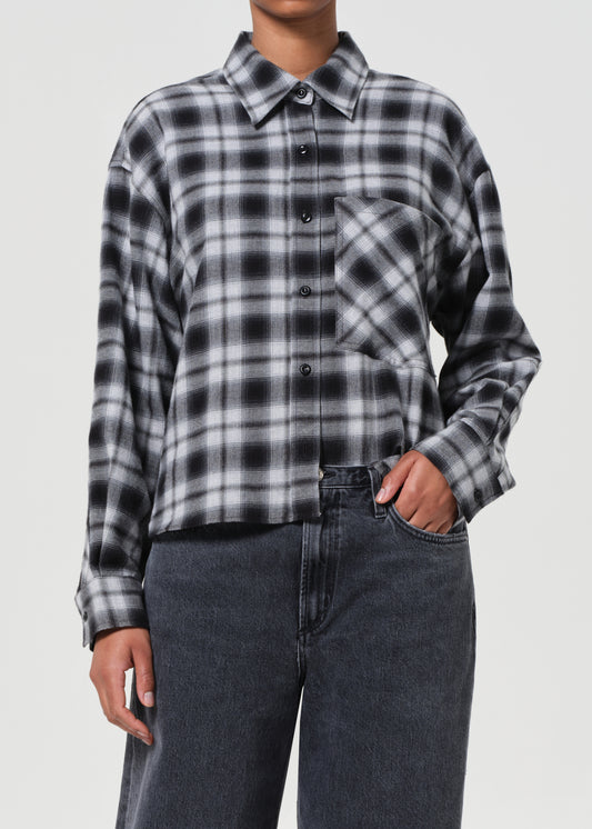 Person wearing a black and white plaid shirt with a plain background