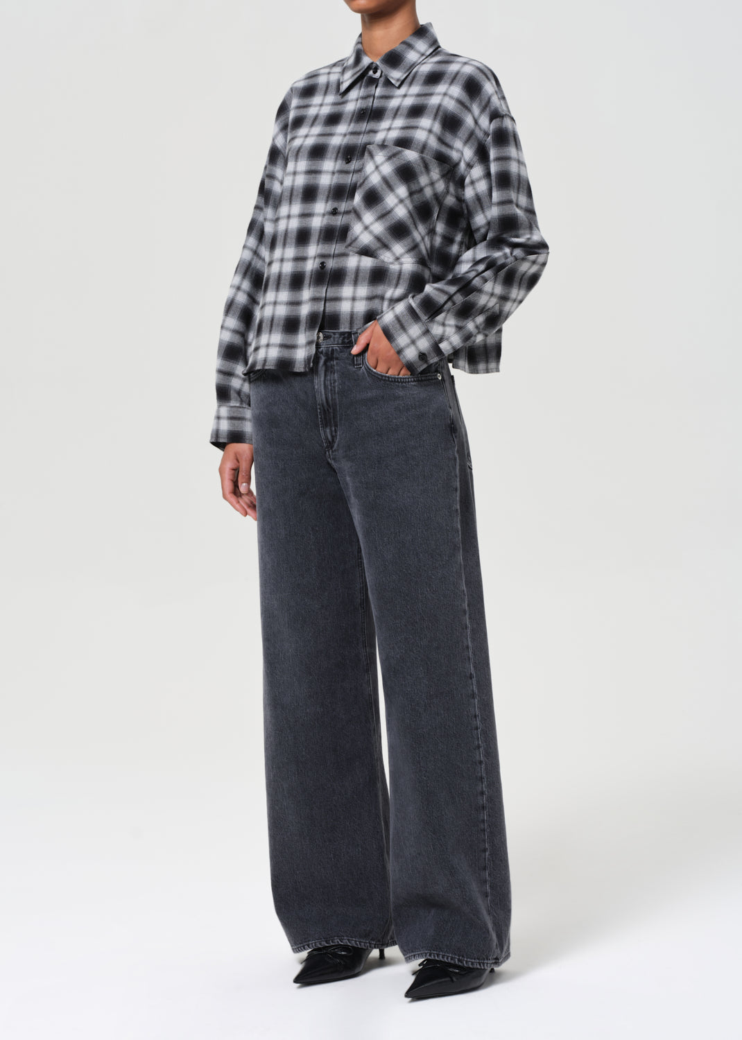 Person wearing a plaid shirt and wide-leg jeans on a white background