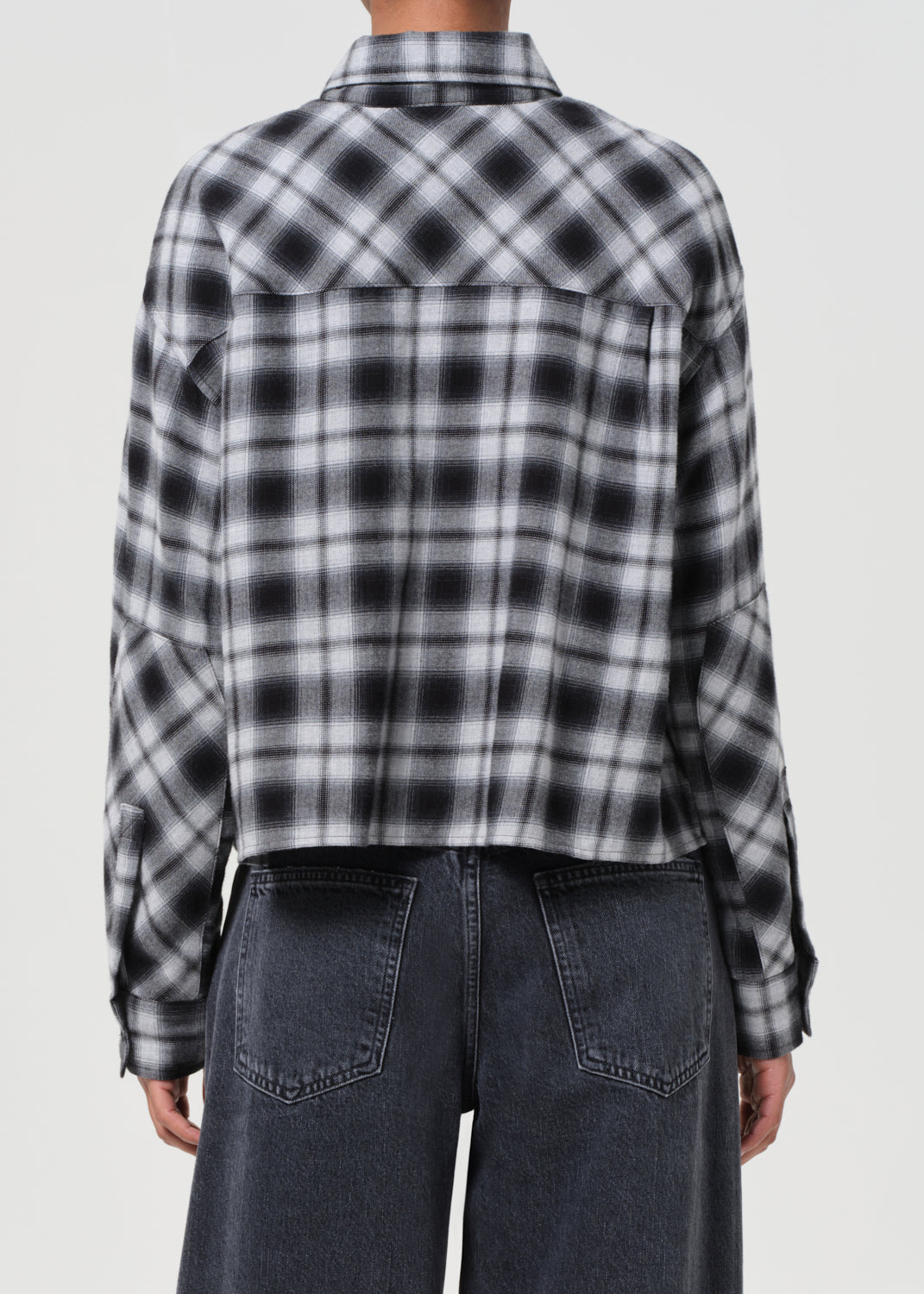 Person wearing a black and white plaid shirt with a gray background
