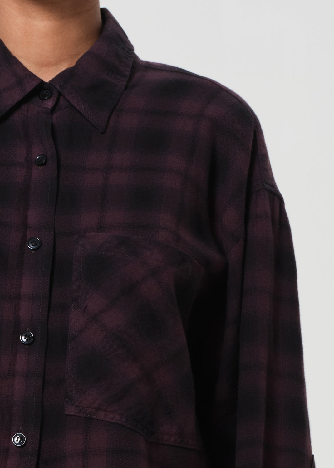 Close-up of a dark plaid shirt with button details on a plain background