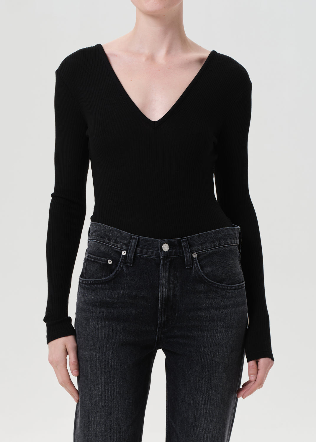 Person wearing a black long-sleeve top and black jeans on a white background