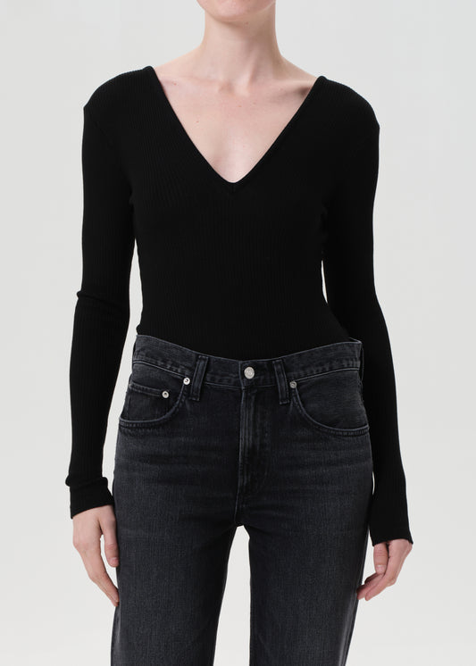 Person wearing a black long-sleeve top and black jeans on a white background