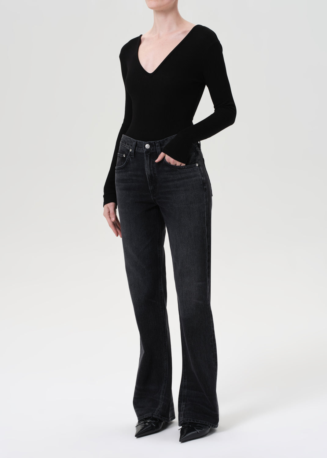 Person wearing a black bodysuit and black jeans on a white background