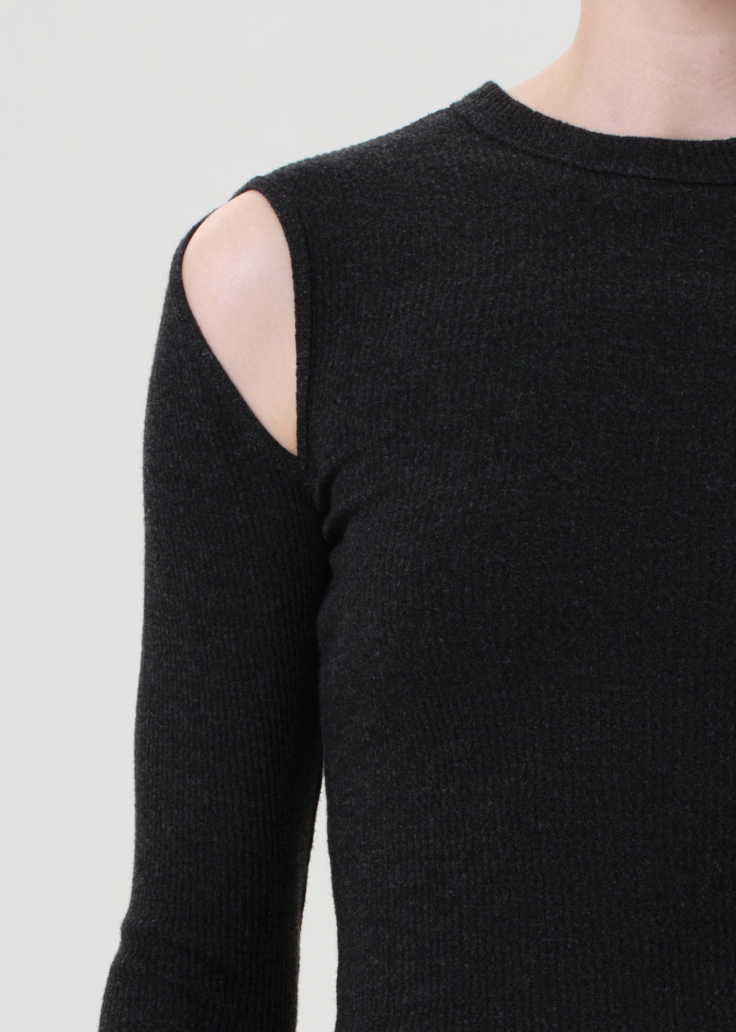 Black long-sleeve top with cut-out shoulder detail on a light gray background