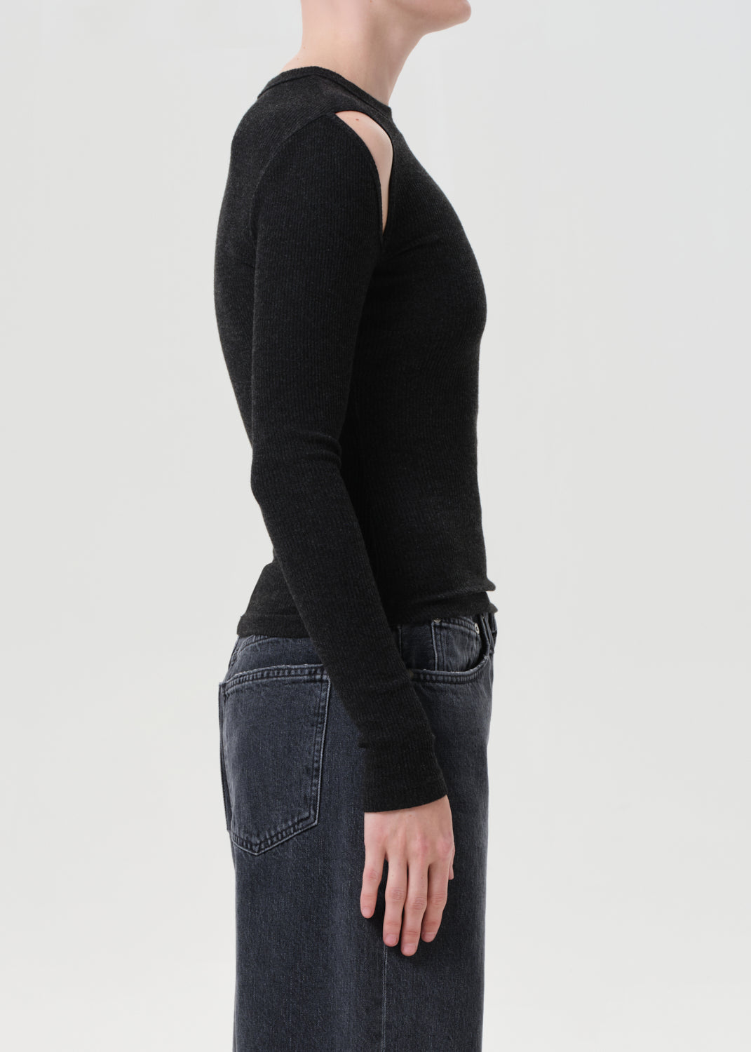 Person wearing a black long-sleeve top with cut-out shoulders on a light gray background