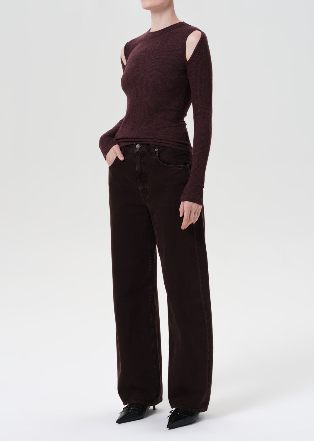 Person wearing a dark brown long-sleeve top and wide-leg pants on a white background