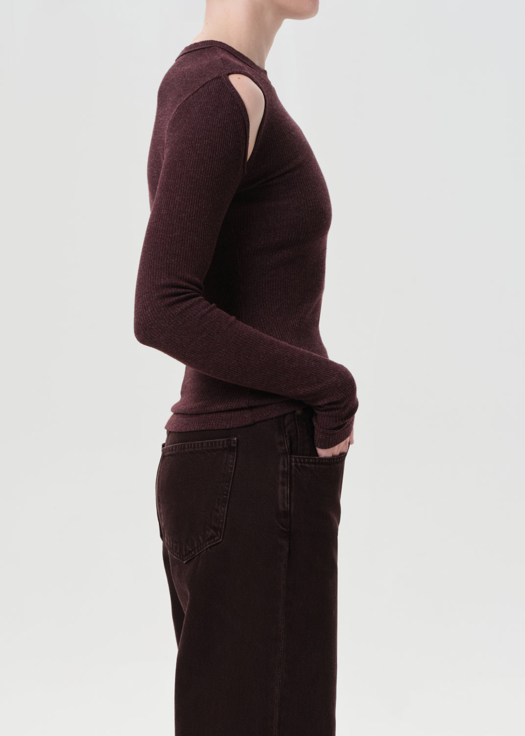 Person wearing a brown long-sleeve top with cut-out design on a light gray background