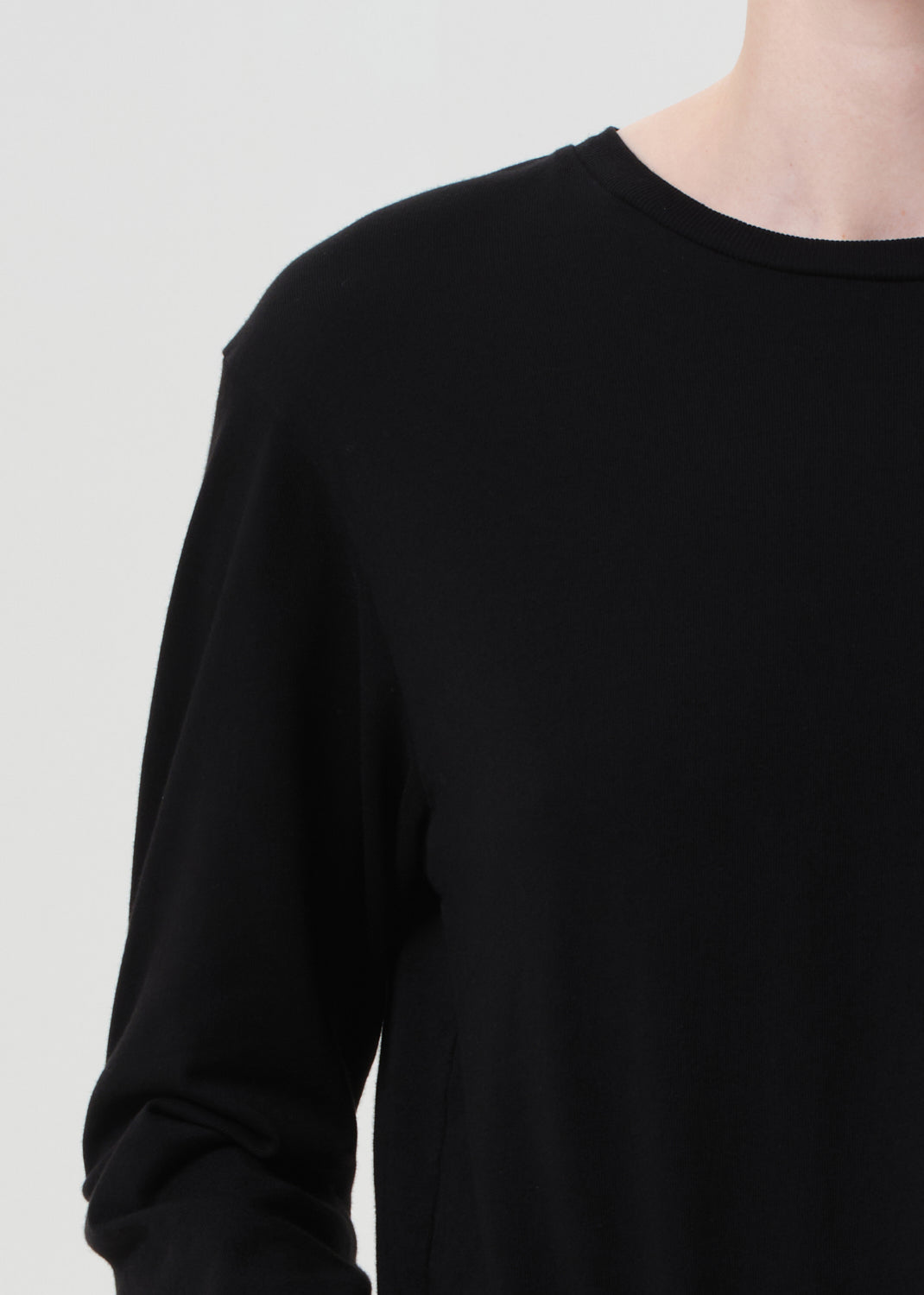 Black long-sleeve shirt worn by a person on a light gray background