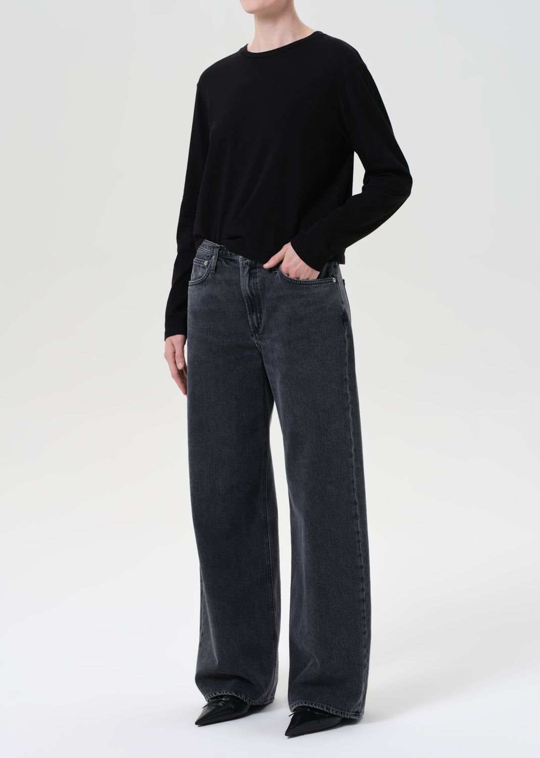 Person wearing a black sweater and dark jeans on a white background