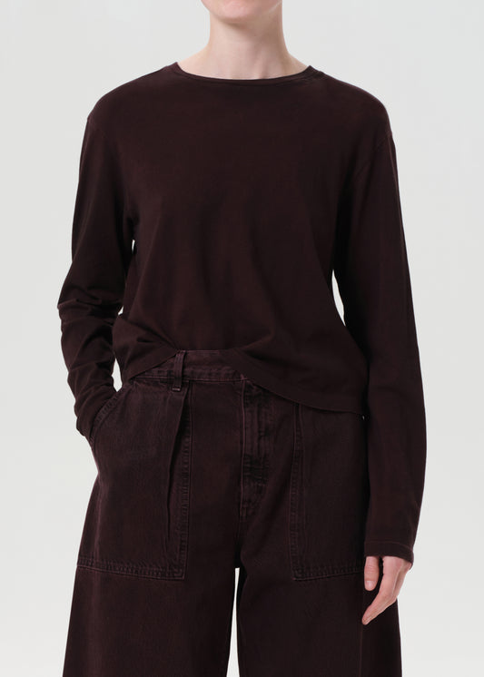 Person wearing a dark brown long-sleeve top and pants on a white background