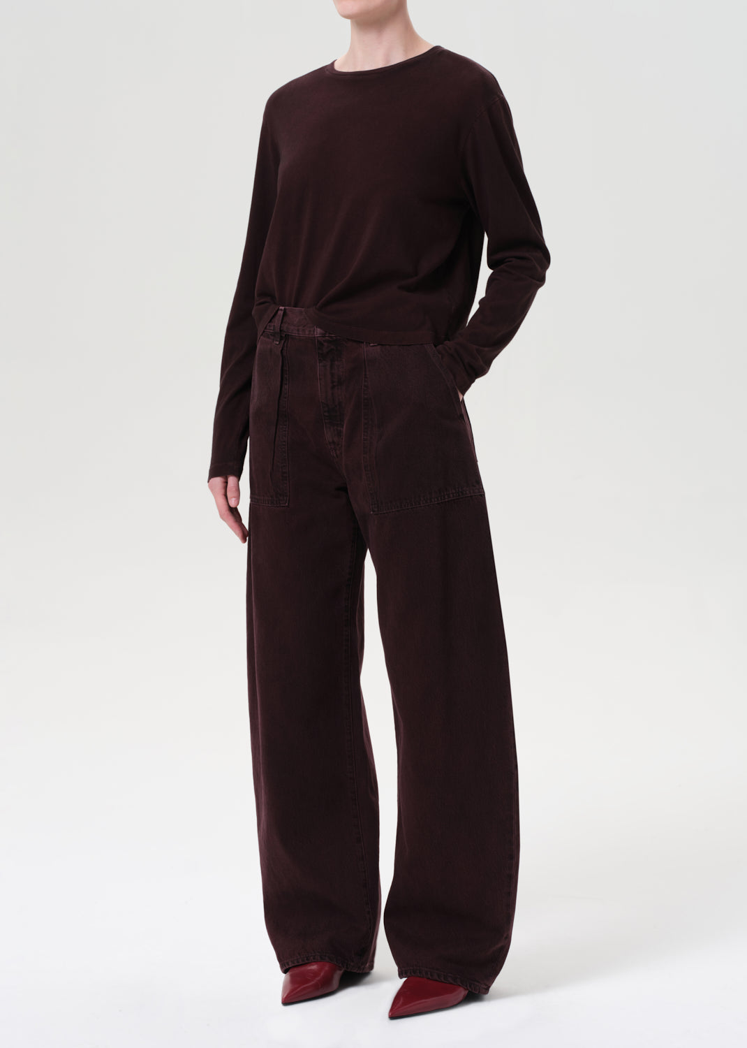 Person wearing a dark brown outfit with wide-leg pants on a white background