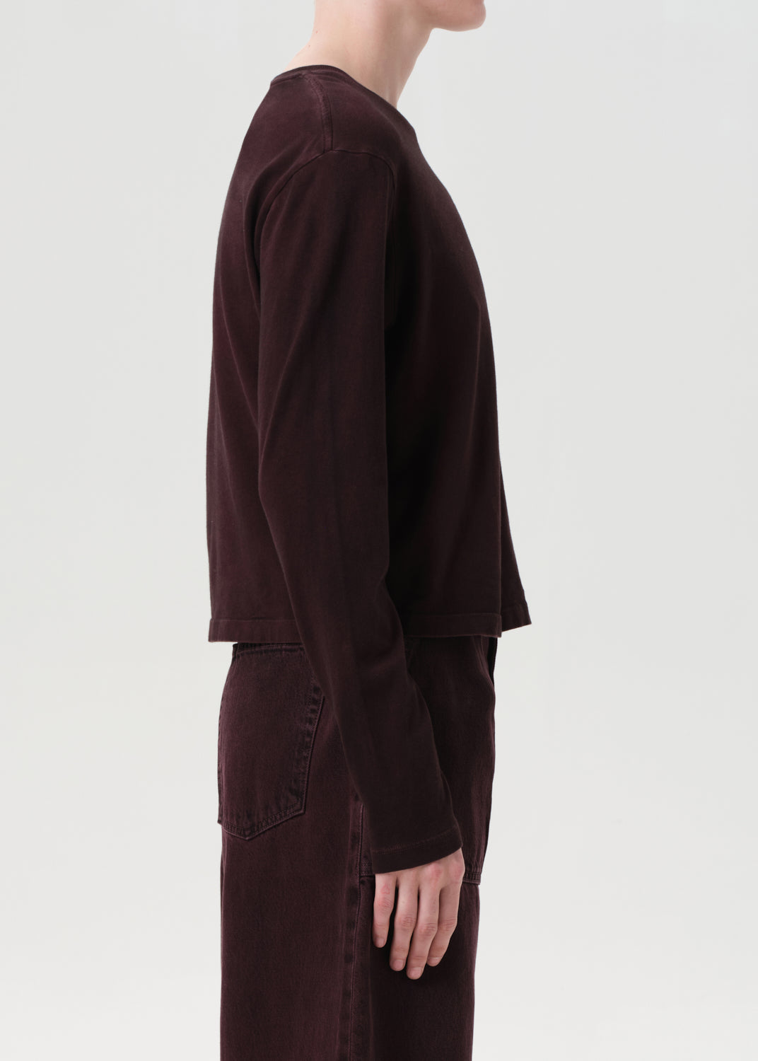 Person wearing a dark brown outfit on a light gray background