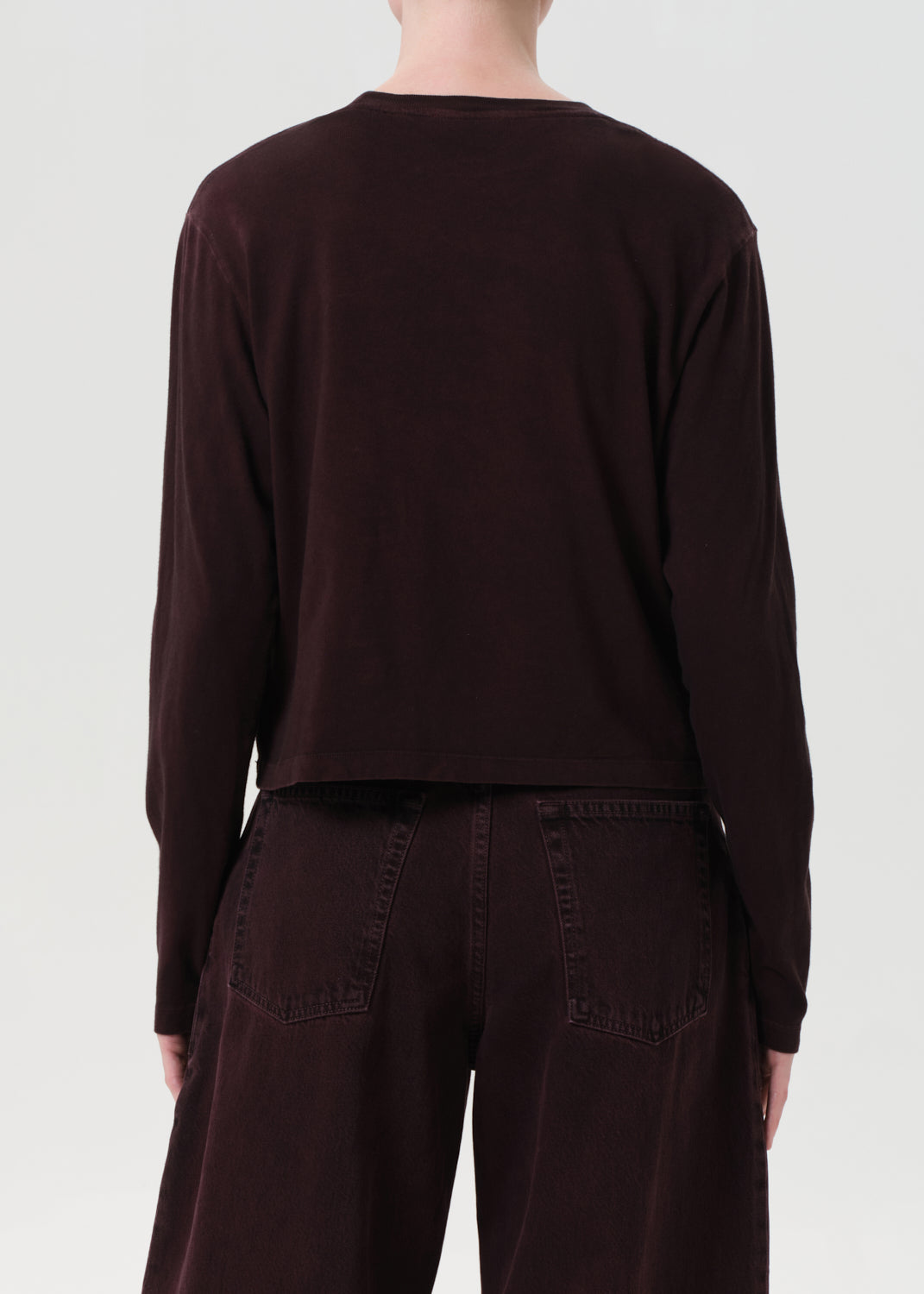 Person wearing a dark brown long-sleeve top and pants on a white background