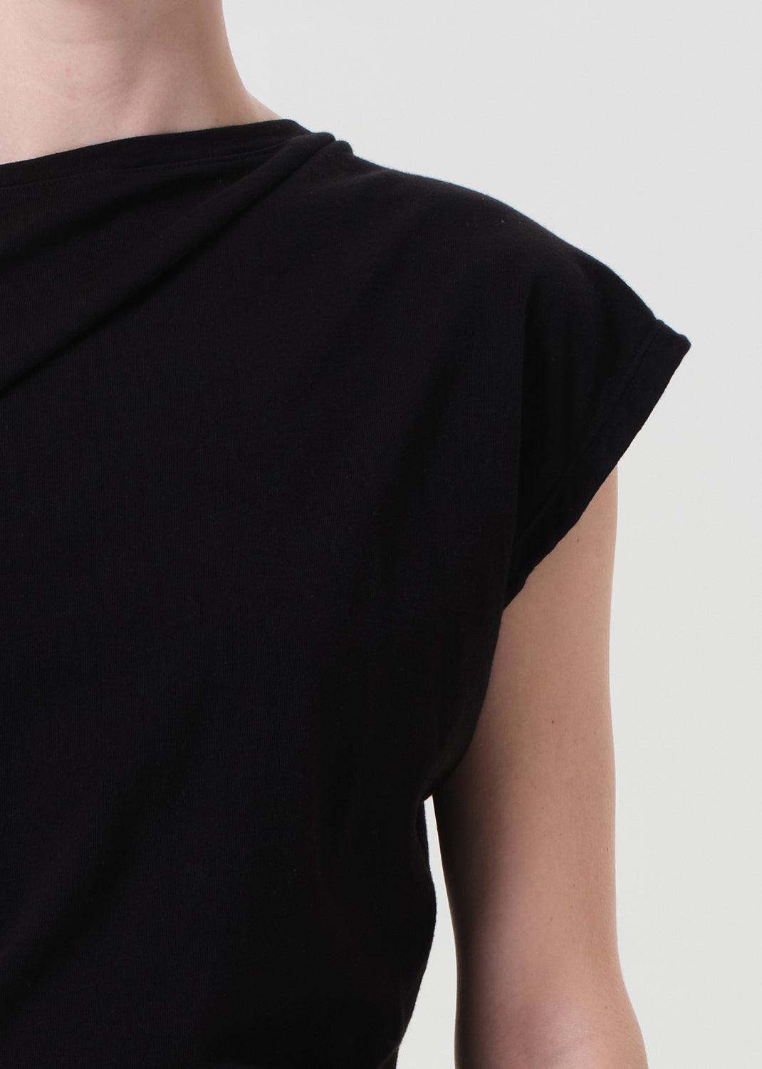 Black sleeveless top worn by a person on a light gray background